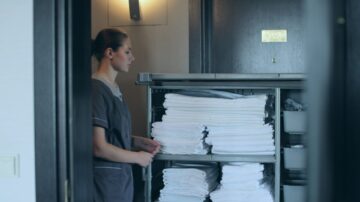 hotelli teenindaja seisab hotelli koridoris, kõrval hunnik puhtaid volditud käterätikuid