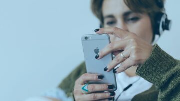 näoga vaataja suunas olev kõrvaklappidega inimene vaatab telefoniekraani